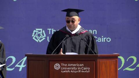A man is standing on a podium, text reads: the American University in Cairo