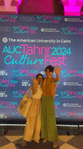 Two girls standing and smiling. Backdrop text: AUC Tahrir CultureFest 2024