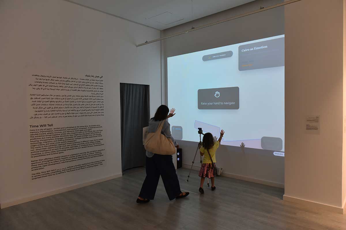 A person and child interact with a wall projection in an art gallery