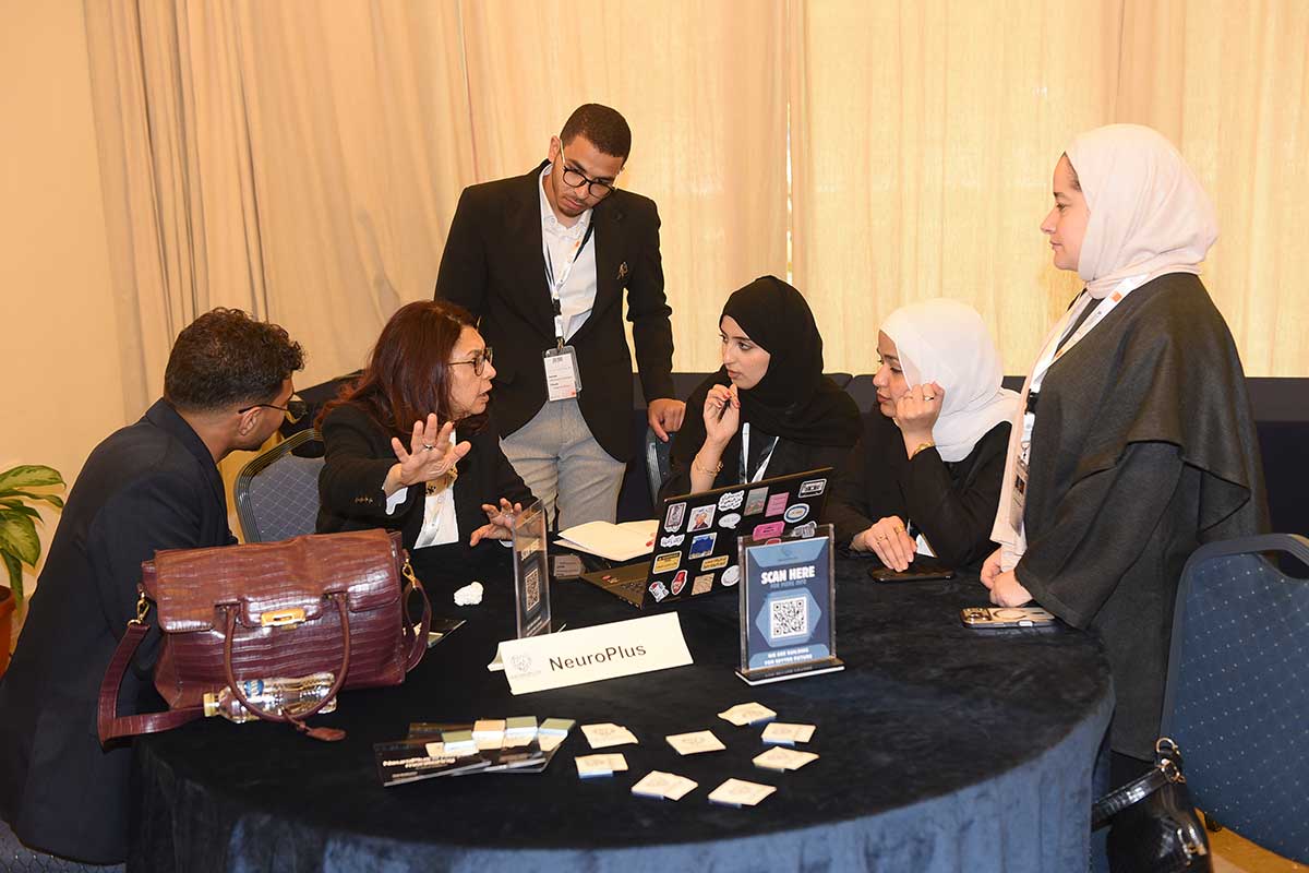 A group of students talk and listen intently to a person speaking at their table