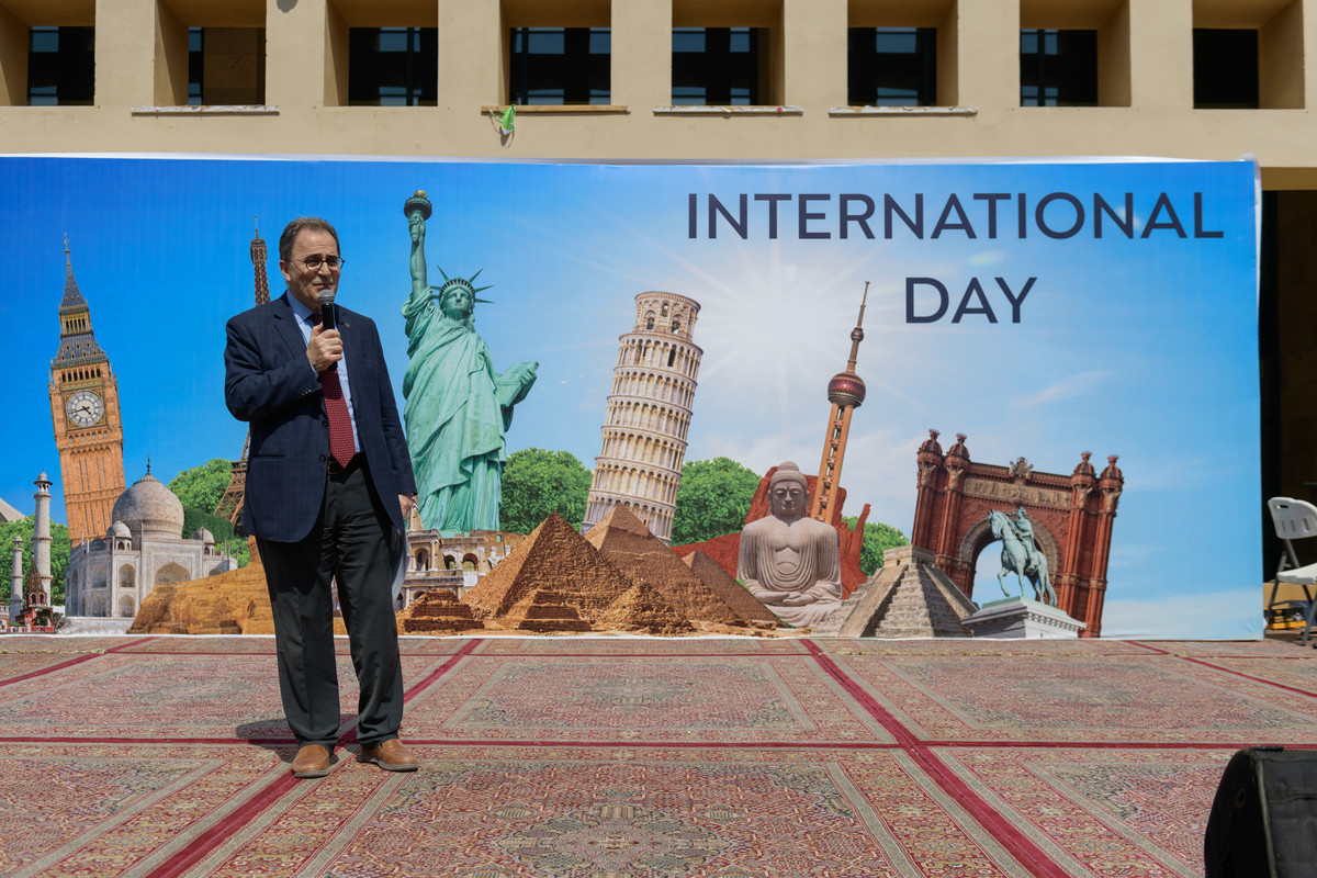 President Ahmad Dallal standing in front of poster showing famous international landmarks