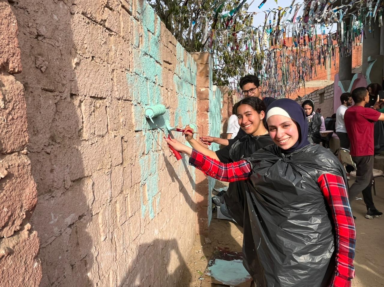 AUC student volunteers paint walls near a home in Fayoum