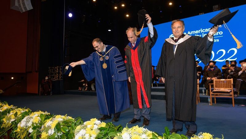 Three men taking off their caps and smiling on stage