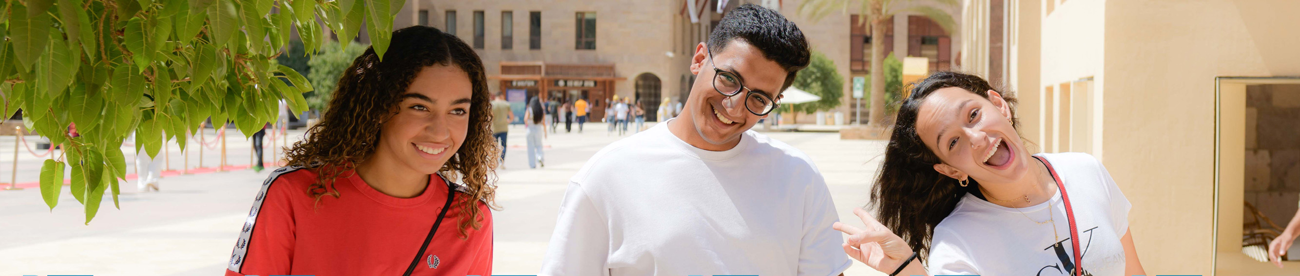 two girls and a boy smiling on university campus