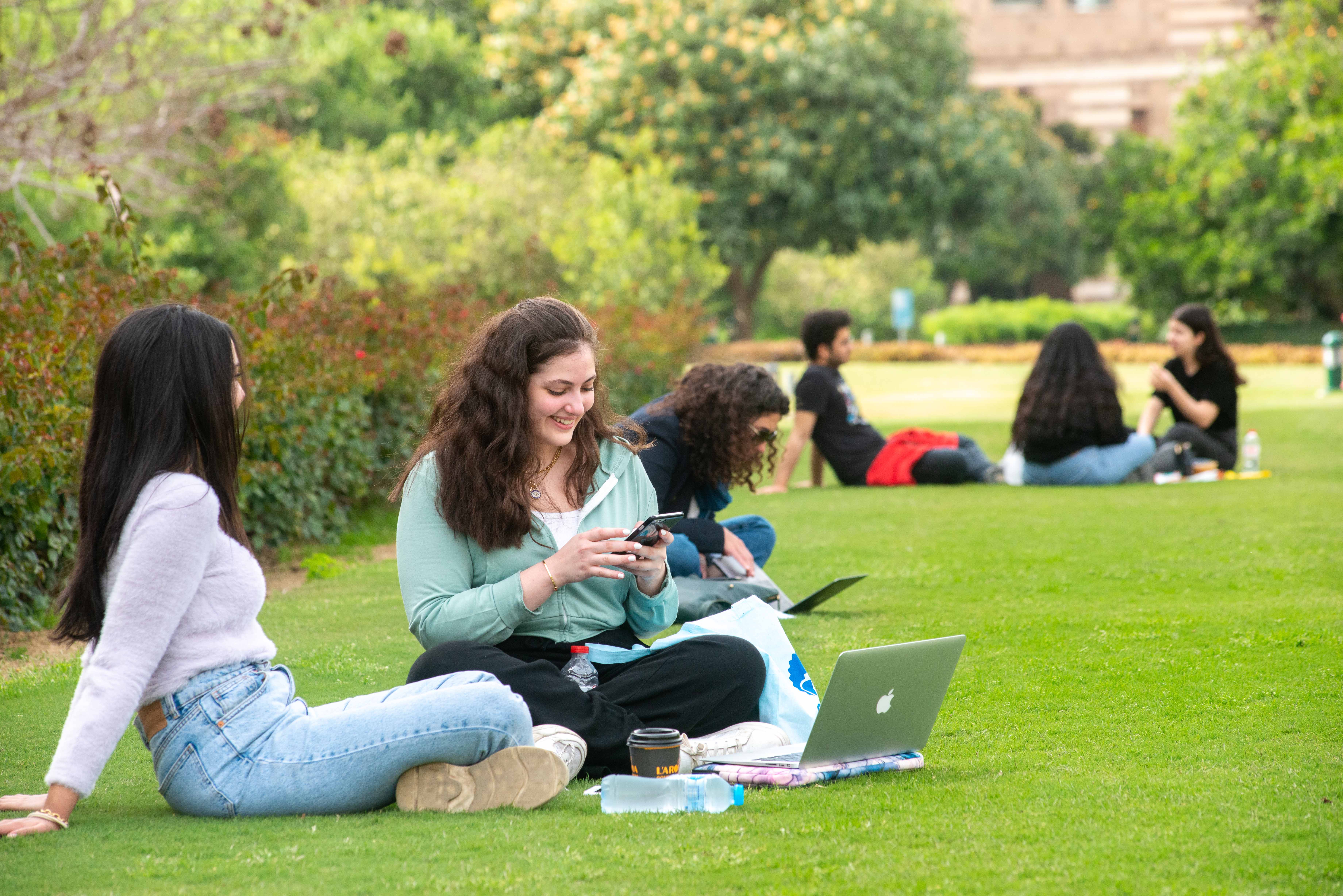 two girls sitting on grass in the garden holding a mobile