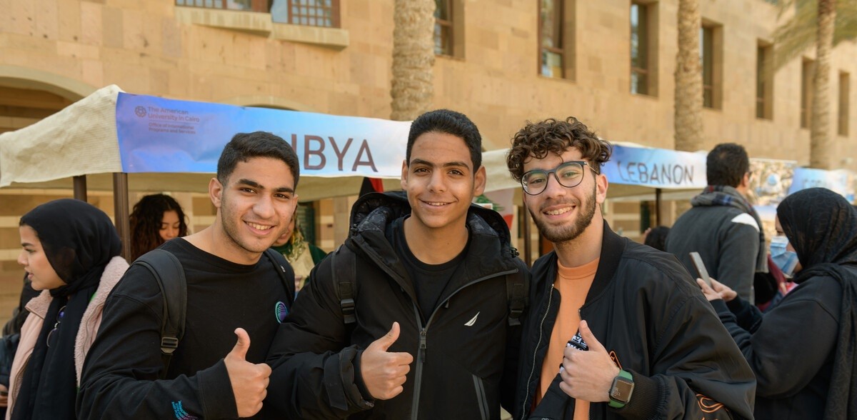 three boys smiling with their thumbs up
