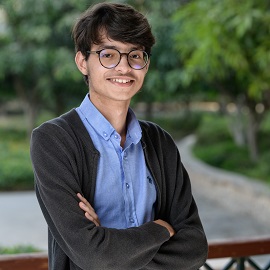 Boy with hands crossed and glasses smiling