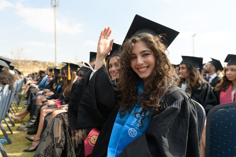 Students in cap in gown sit at commencement