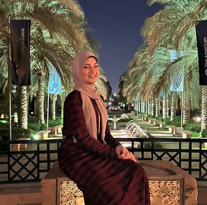 Veiled girl sitting with trees in background