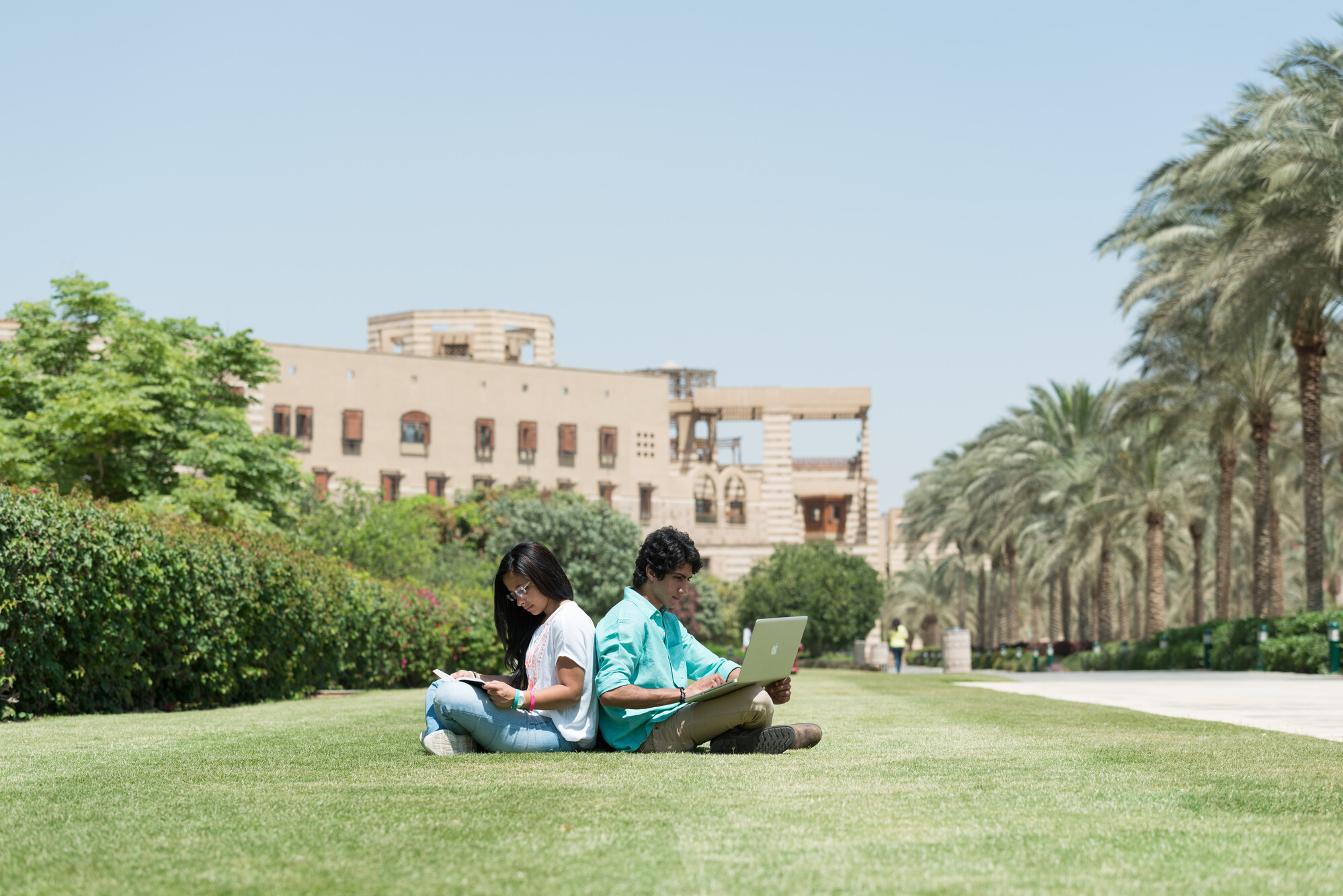 Boy and girl sitting back to back on grass