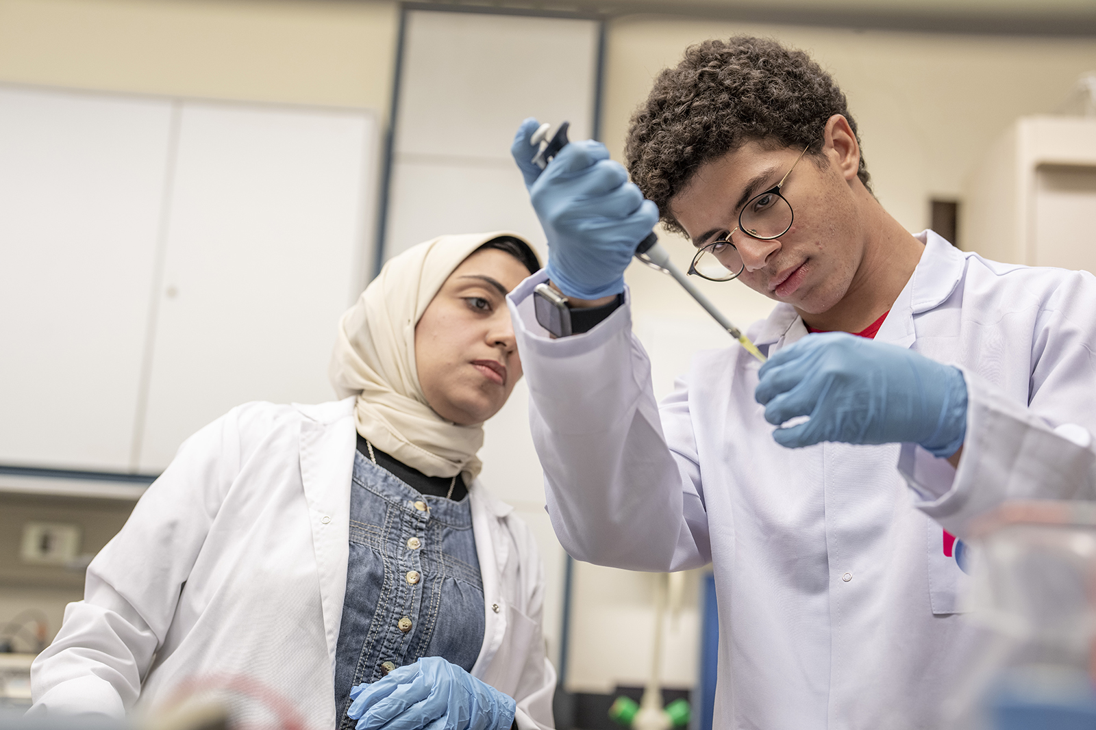 Students with white coats working with chemicals in lab