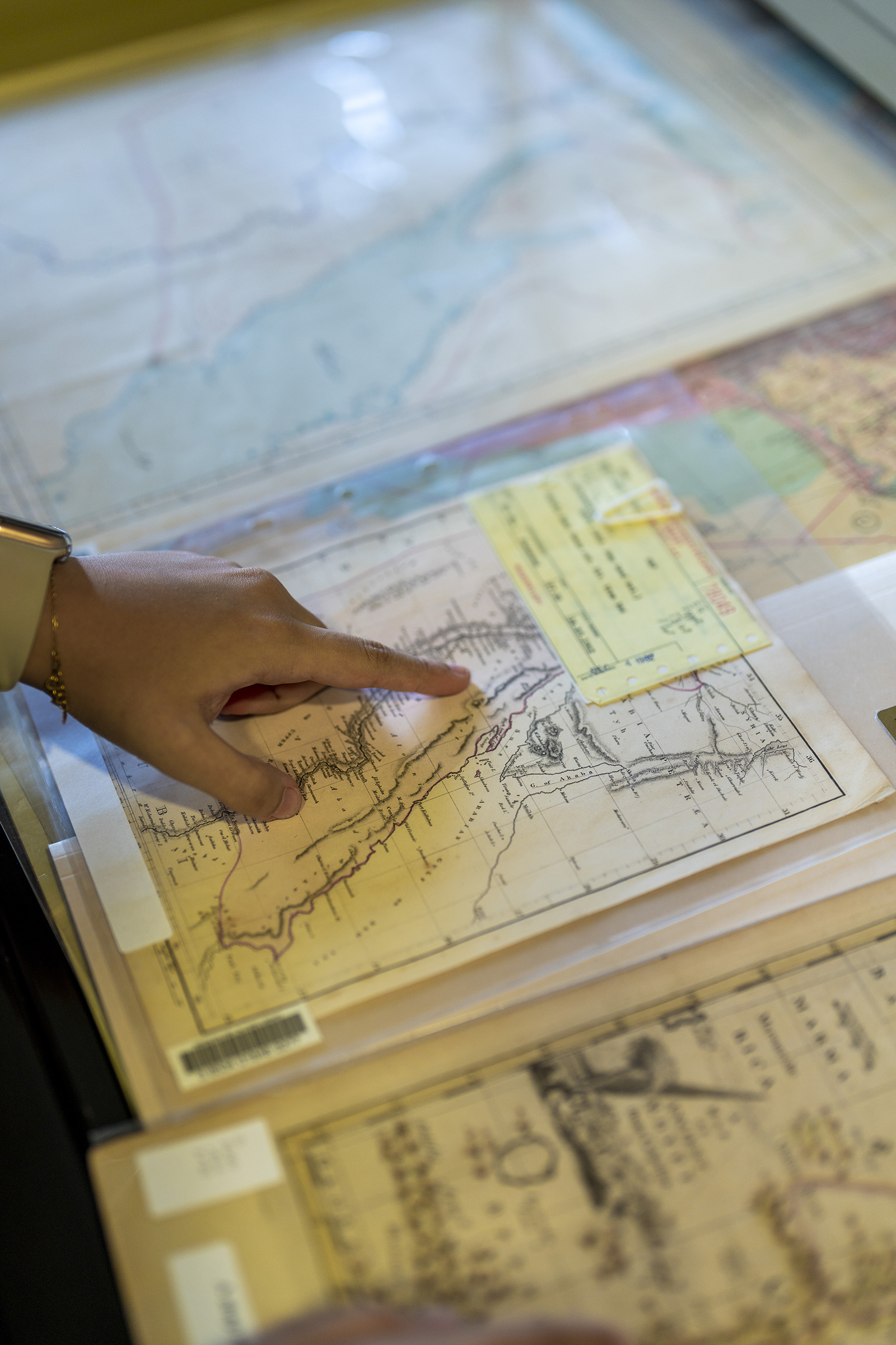 closeup on student hand pointing at old maps in library