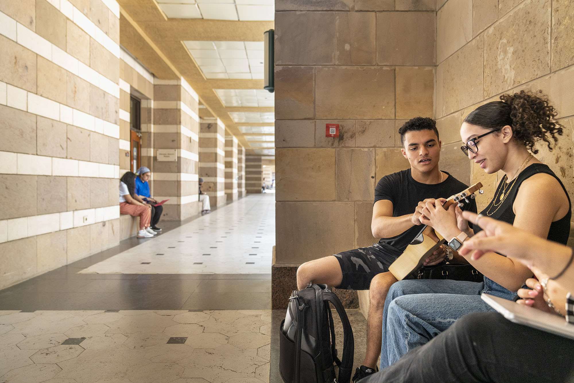 A girl and boy on AUC campus playing the guitar