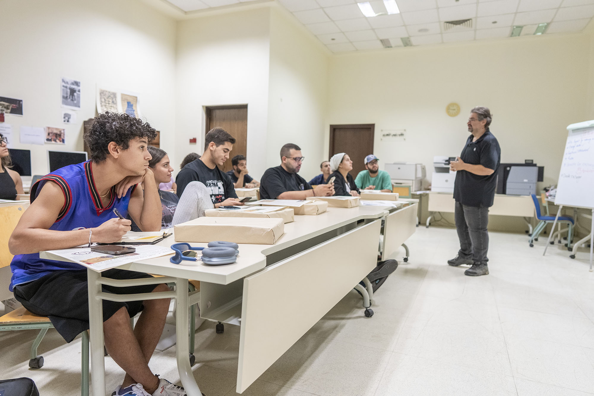 Students sitting in class on their desks with their professor explaining