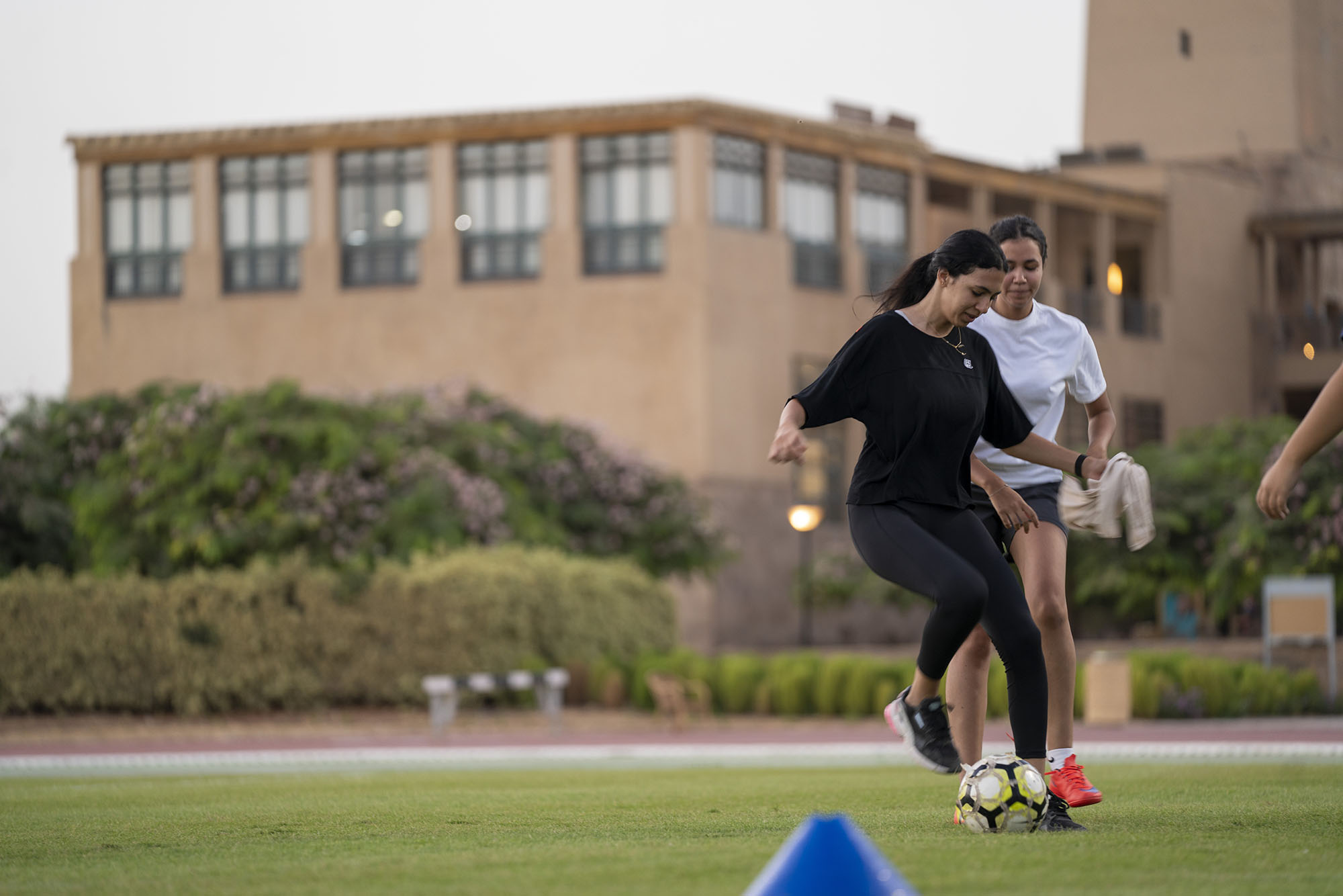 Two girls playing soccer in a soccer field