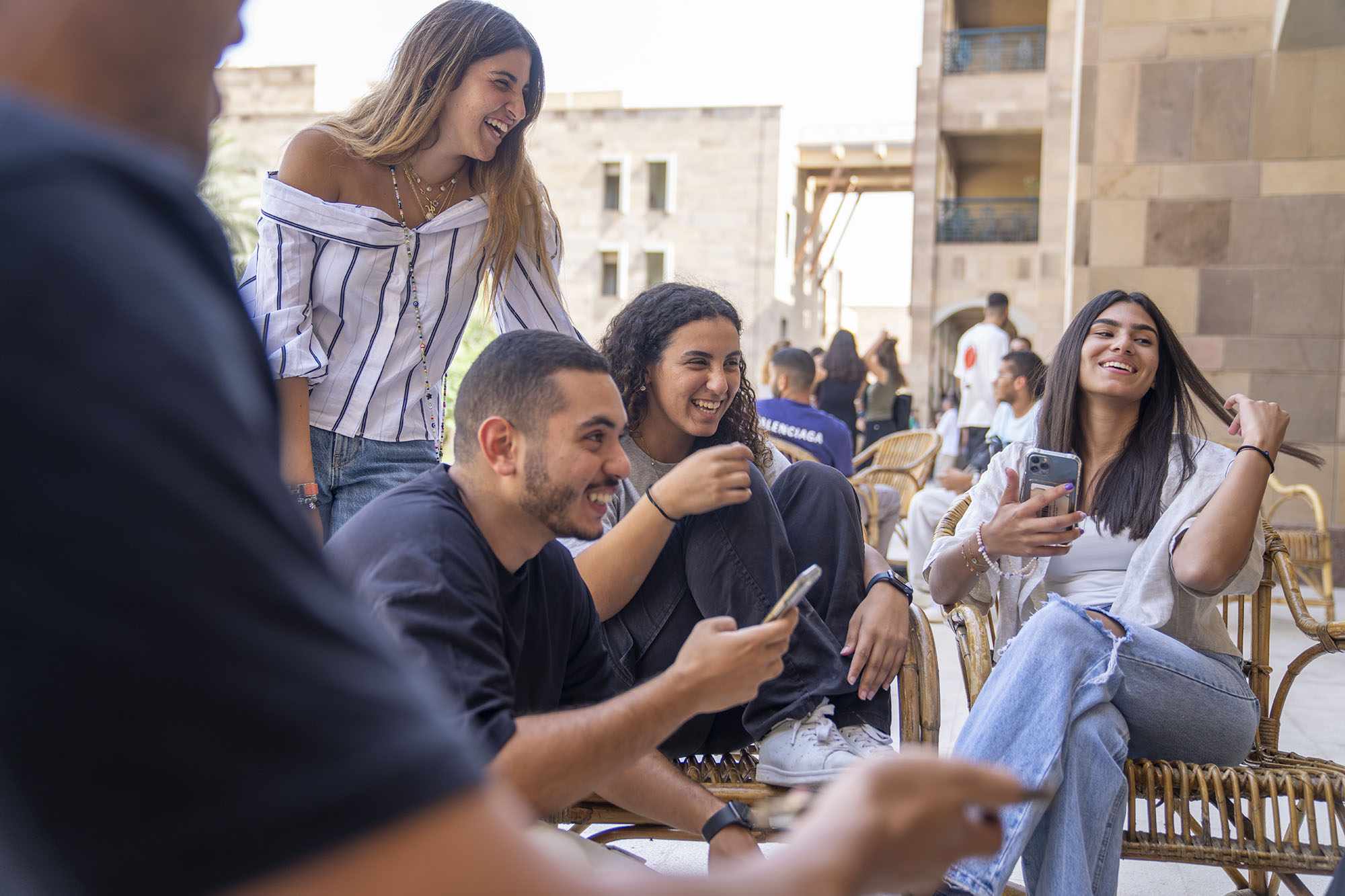 A group of boys and girls sitting on chairs outdoors laughing together