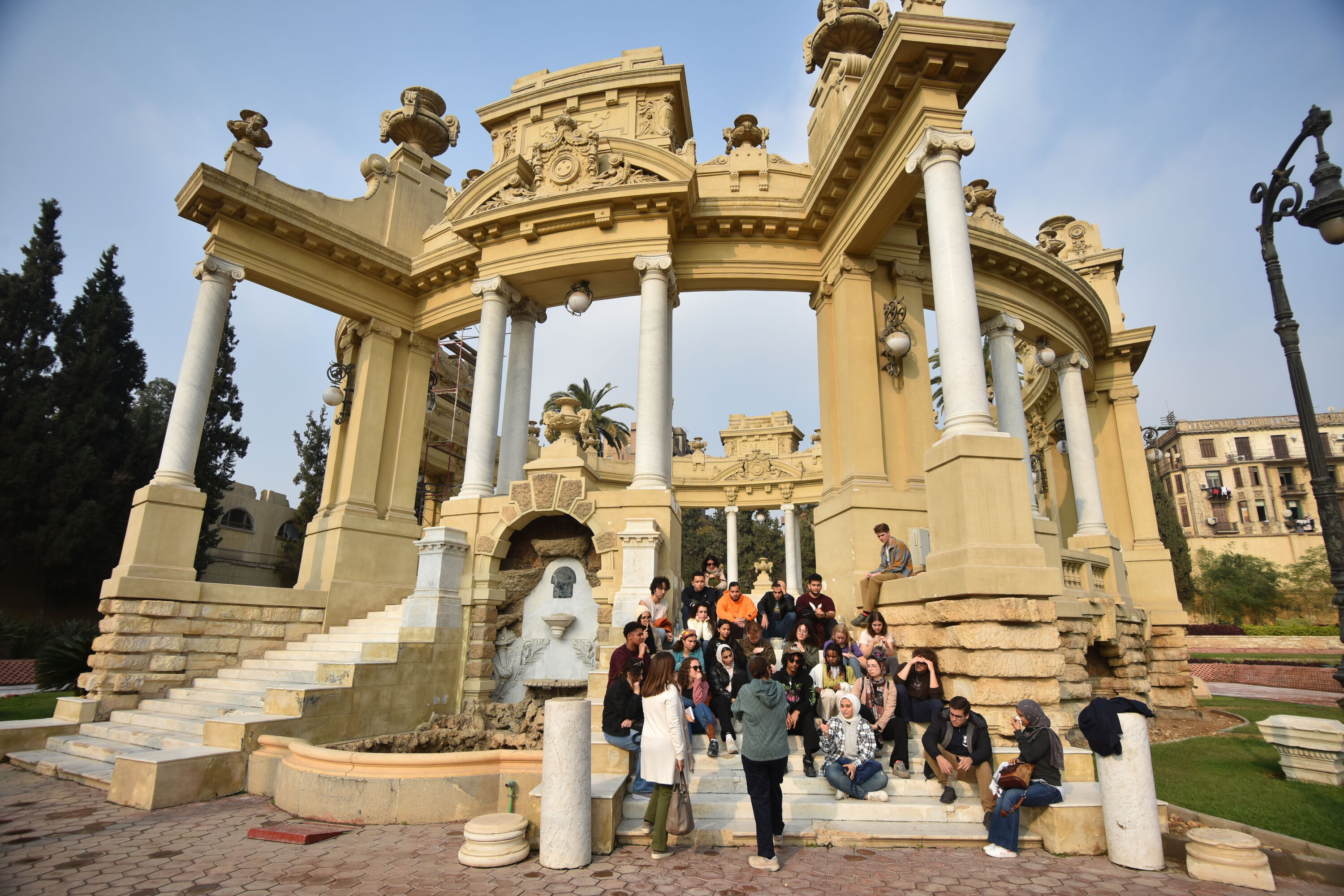 A group of students sitting stairs by a historic temple