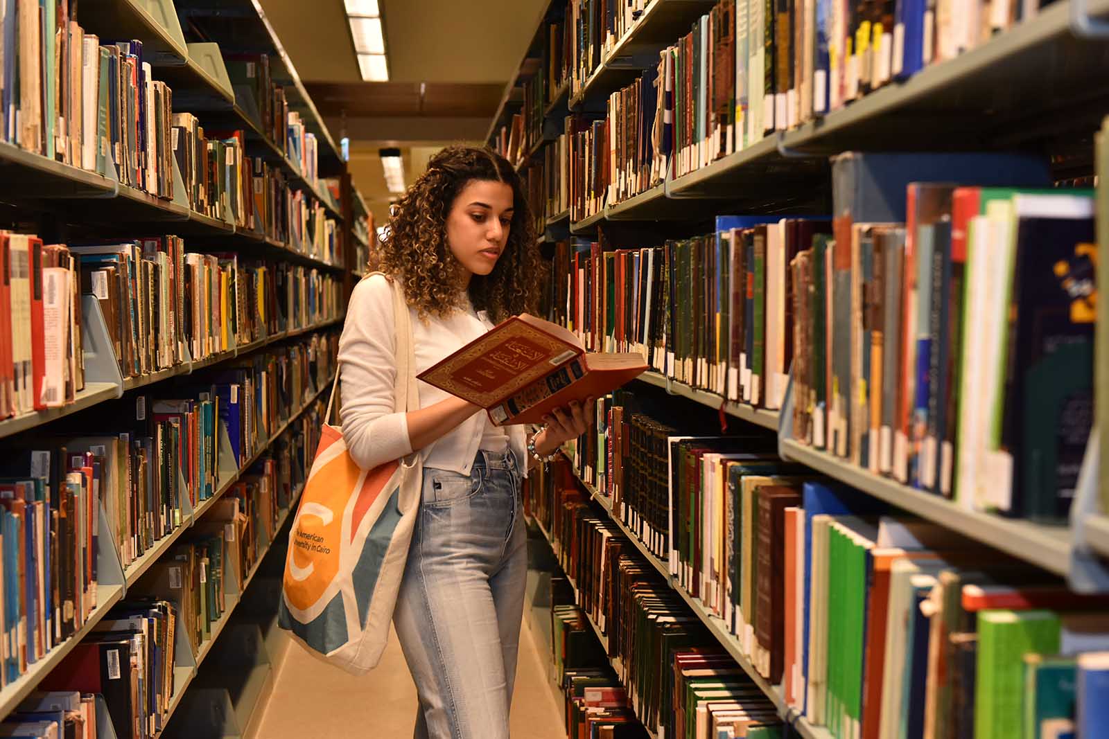 female student looking through a book in the library