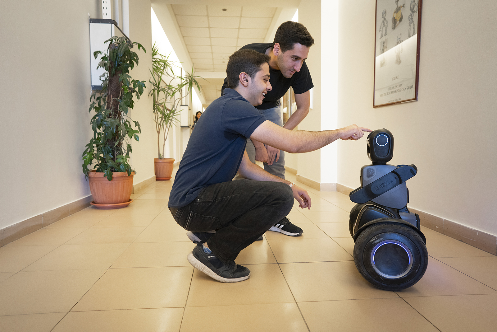 A corridor with two students trying out a robot