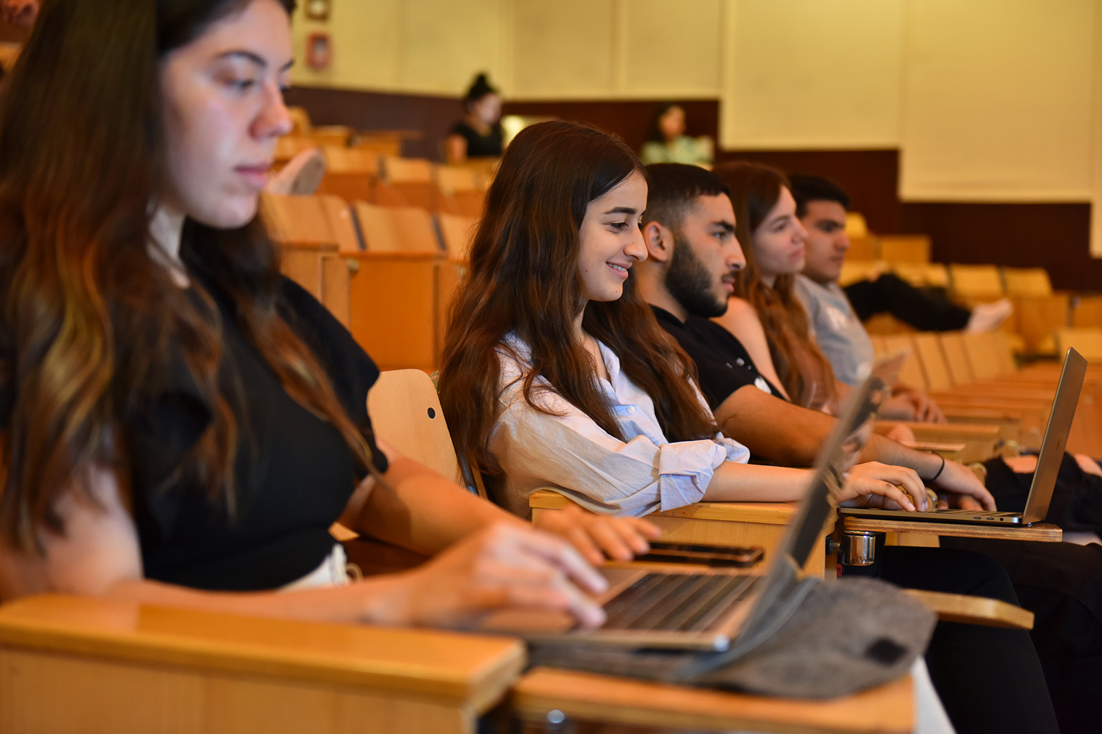 students sitting in a class with their laptop on the desk