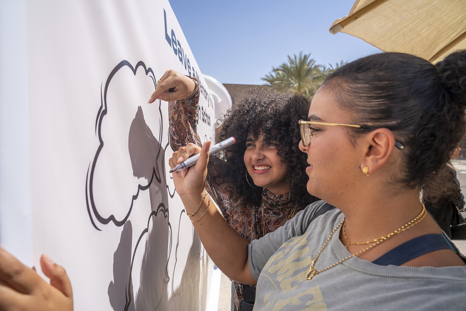 Two students writing on a white cardboard