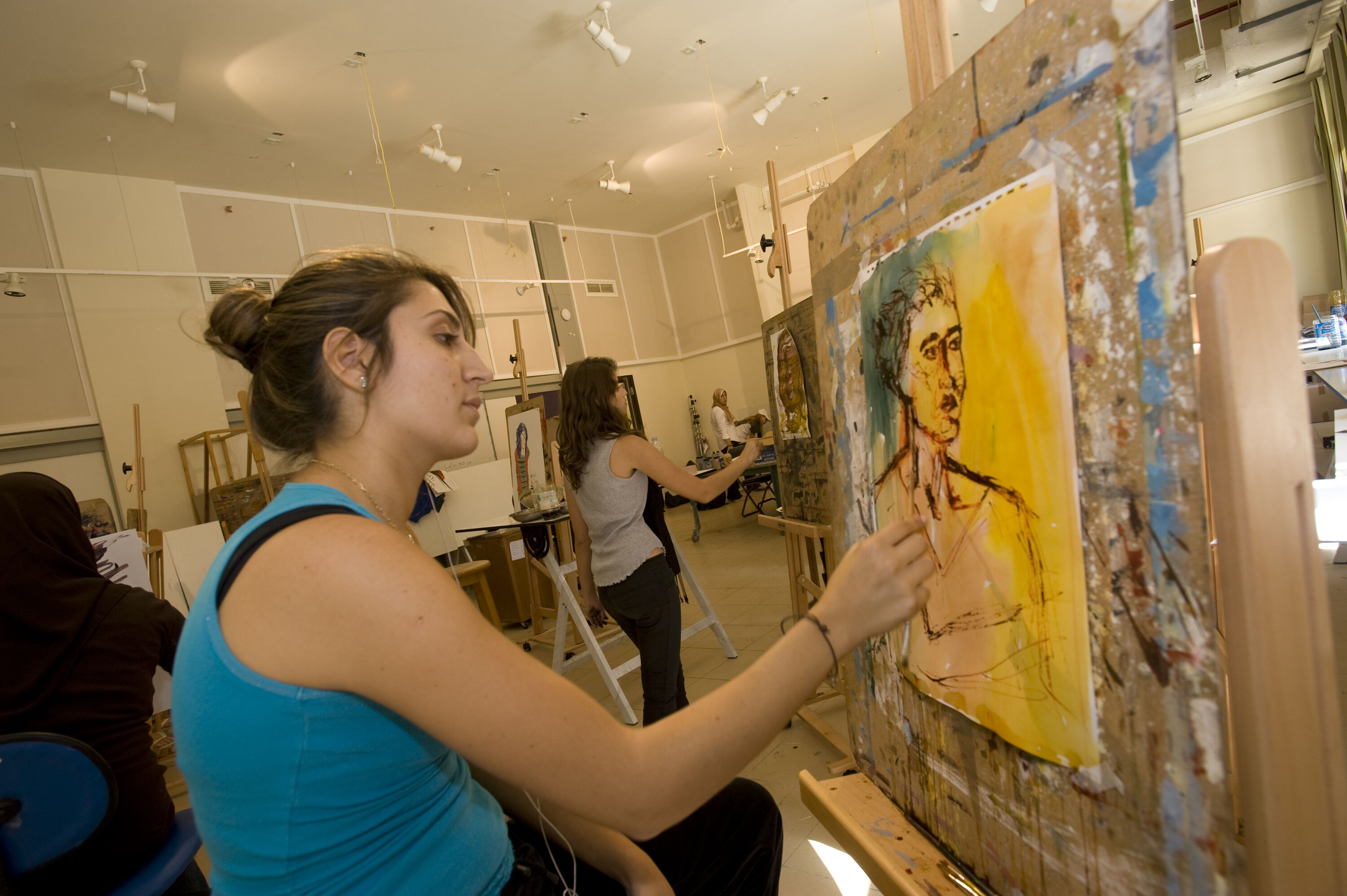 Girl in art classroom drawing a portrait of a man on a canvas stand