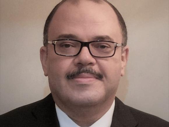 Headshot of a man wearing a suit with glasses