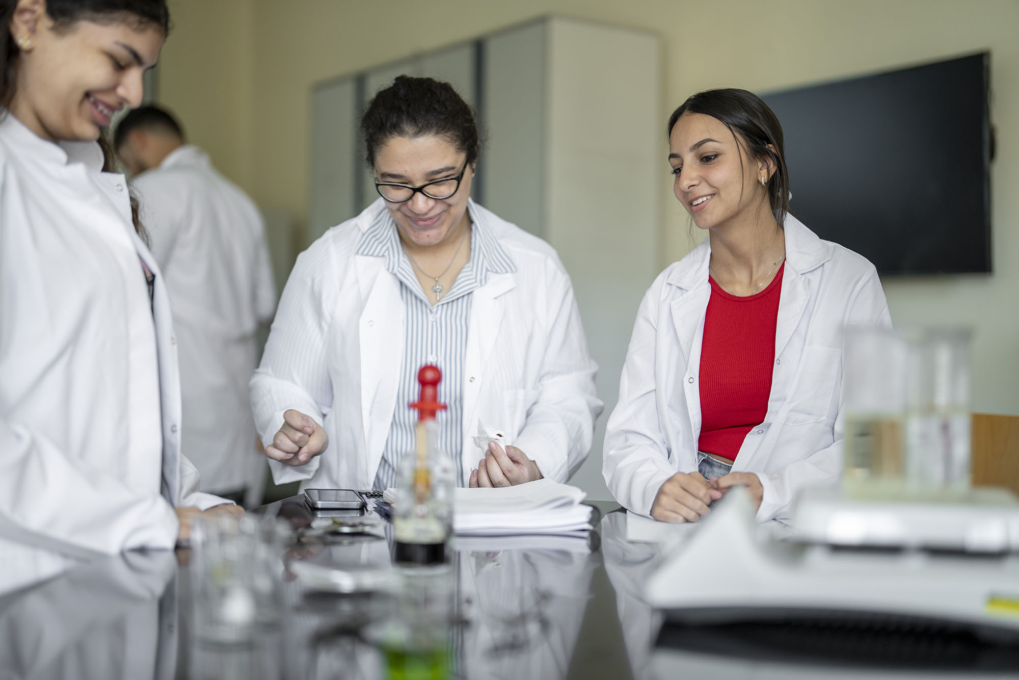 biology program image of group of  female students in white coats working with science equipment 