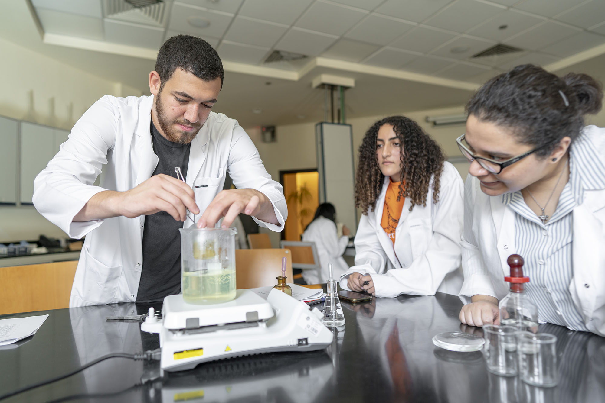 students with white coats working in lab with chemicals