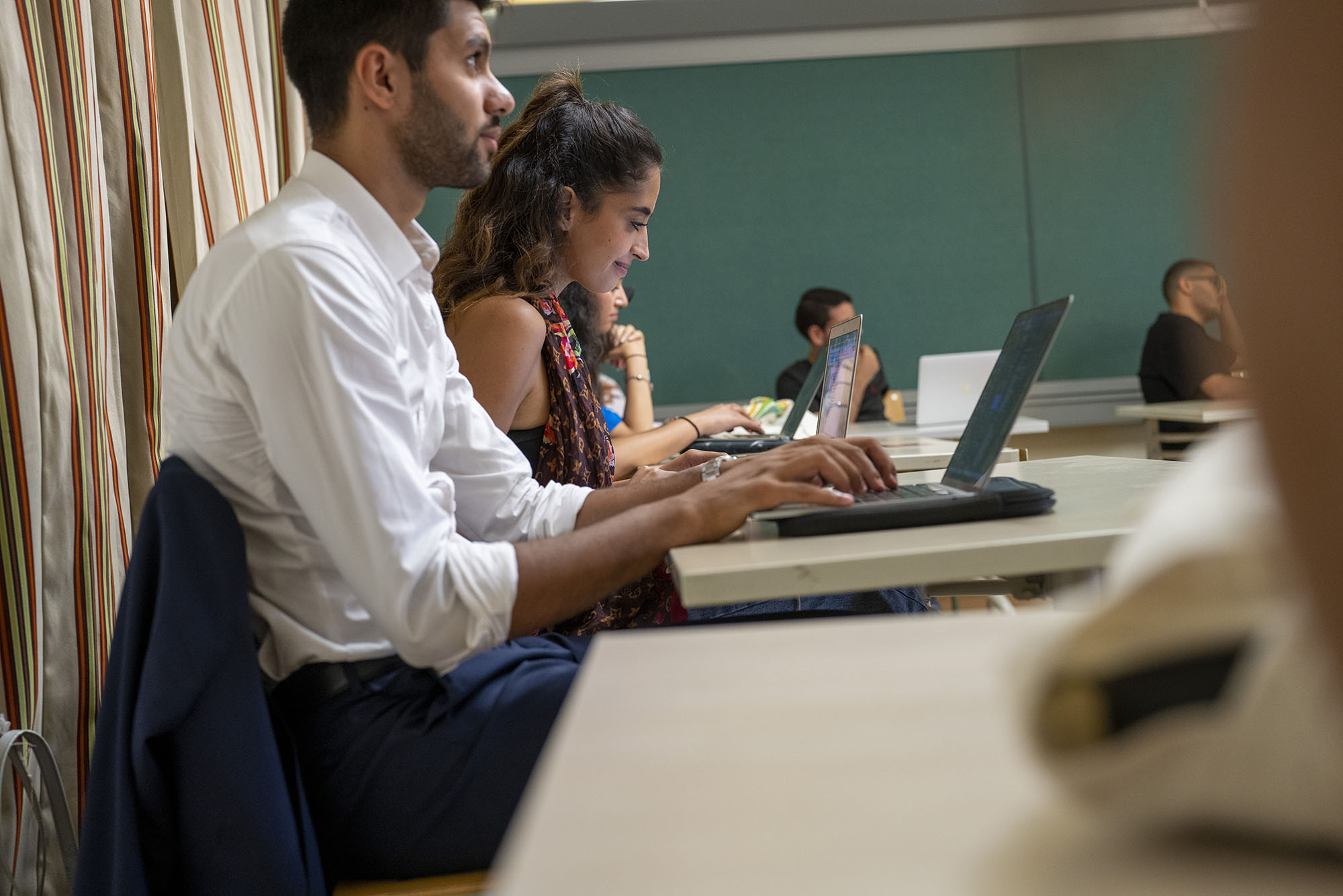 International management cems banner image of students with laptops attending class and taking notes