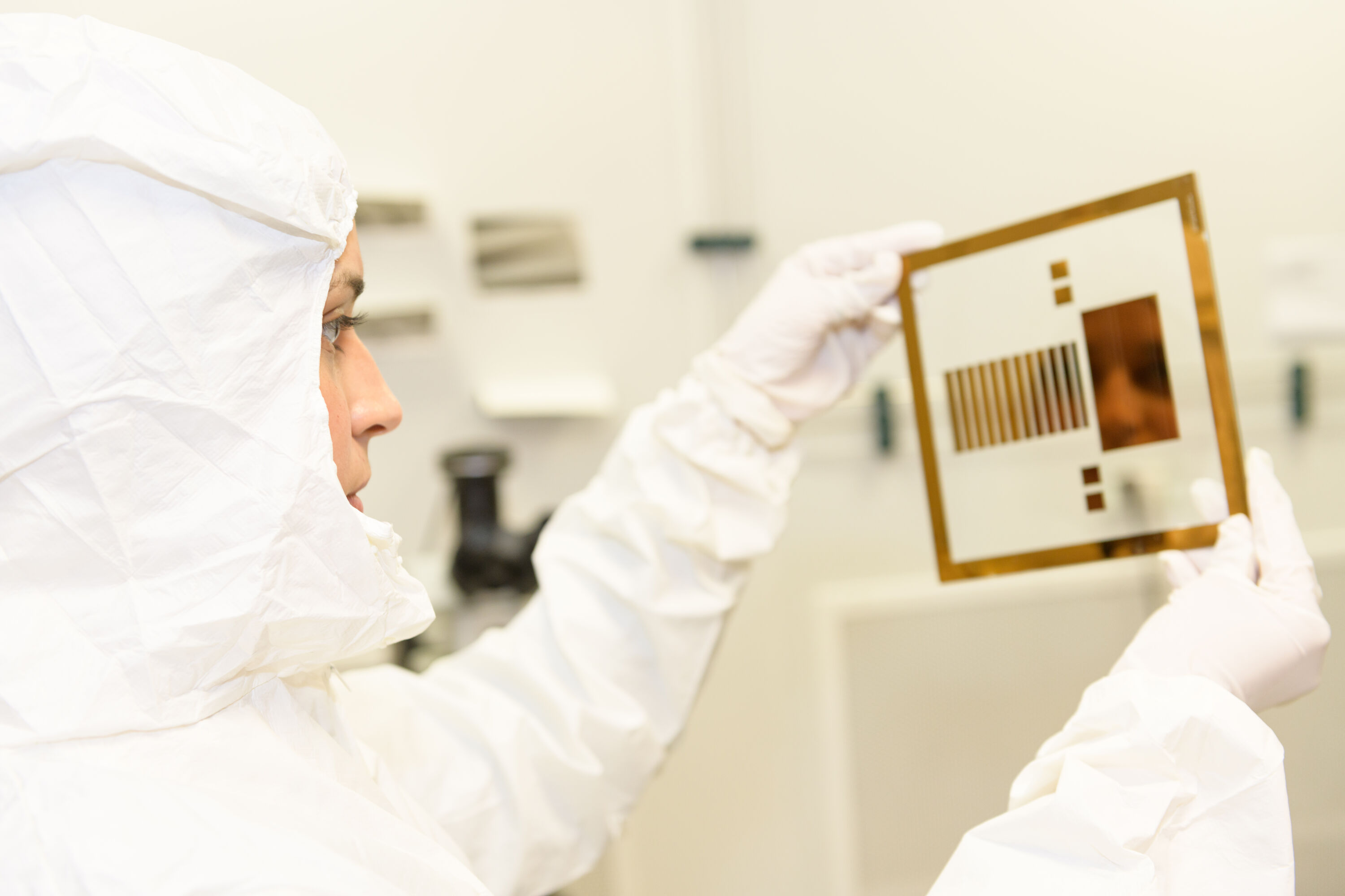 student wearing full white lab clothes working with equipment in sciences lab