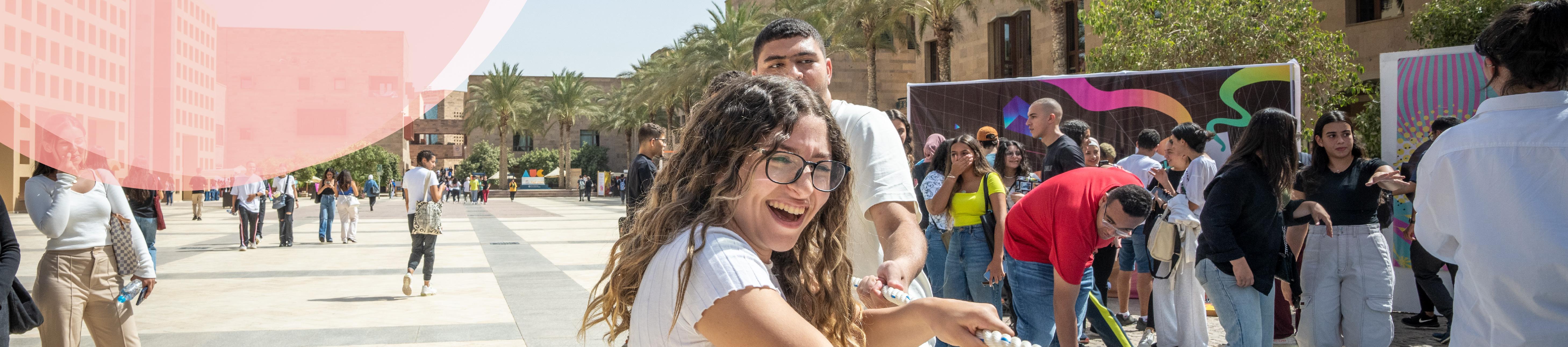 Girl in auc plaza playing tug of war smiling