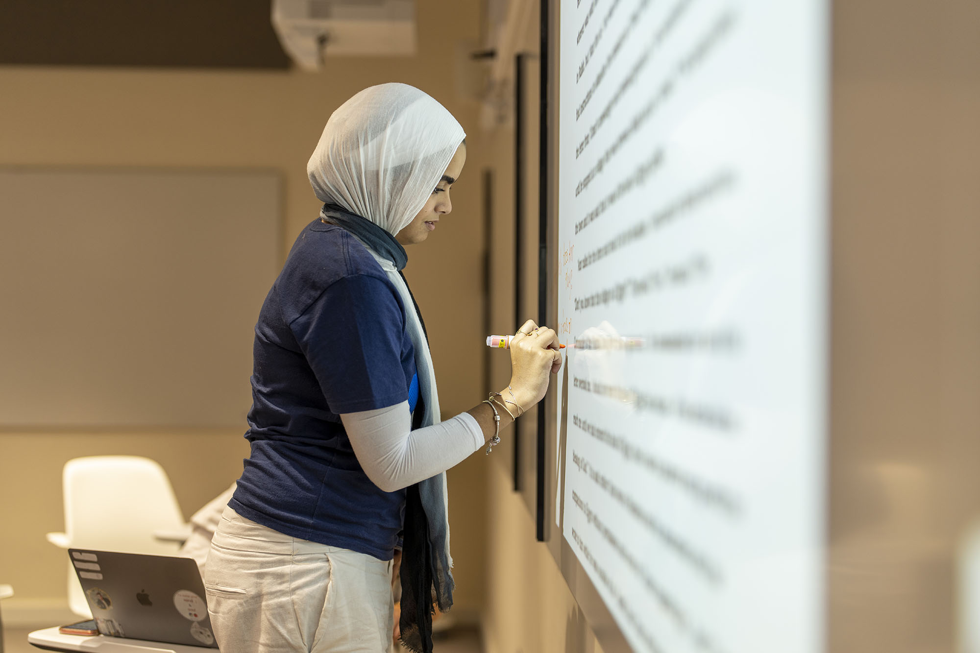 TESOL program image of veiled student writing on white board information