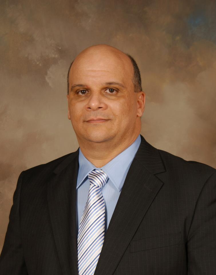 Headshot of a bald man with suit and tie