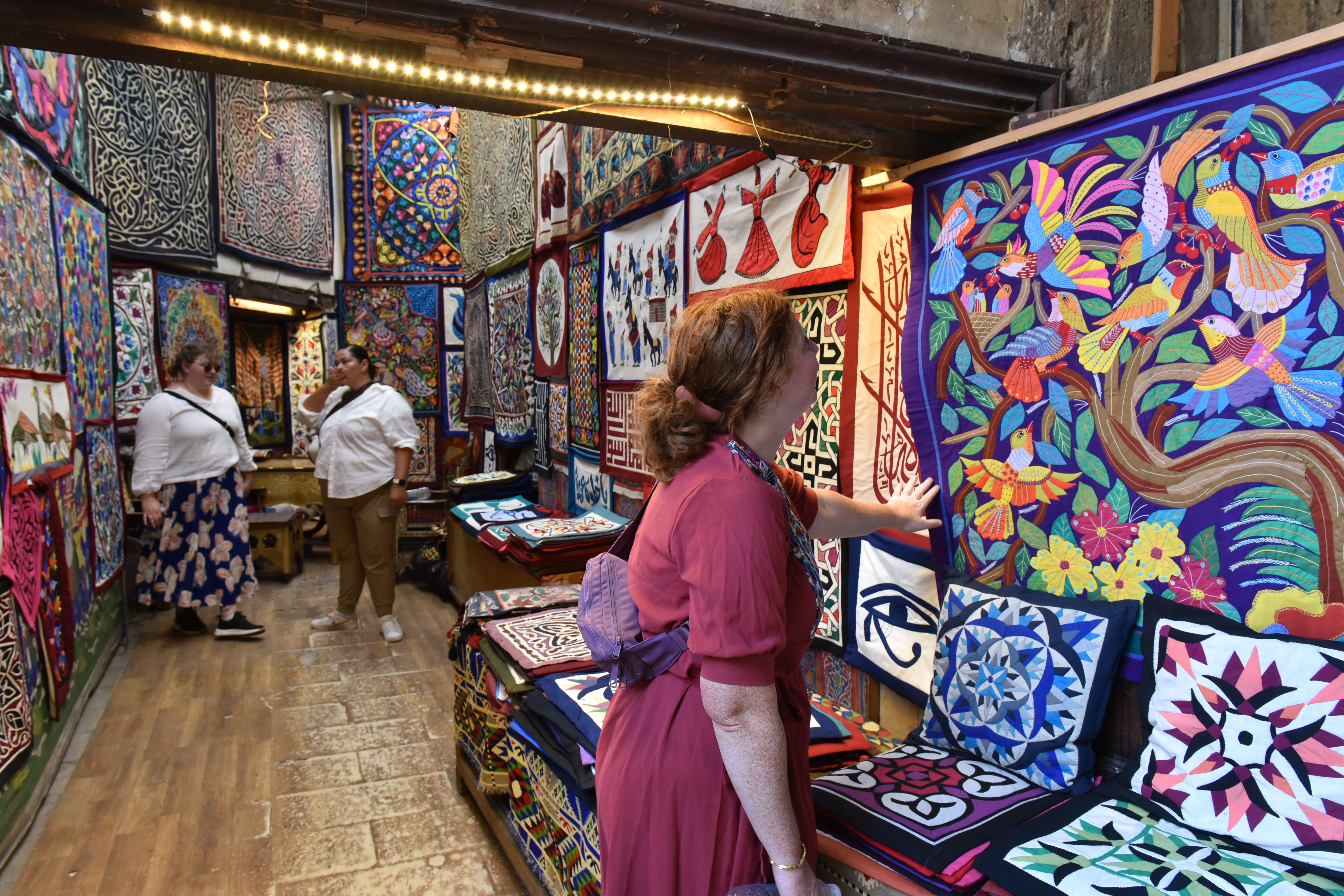 Woman in Cairo's tentmaker bazaar looking at a colorful piece of patchwork