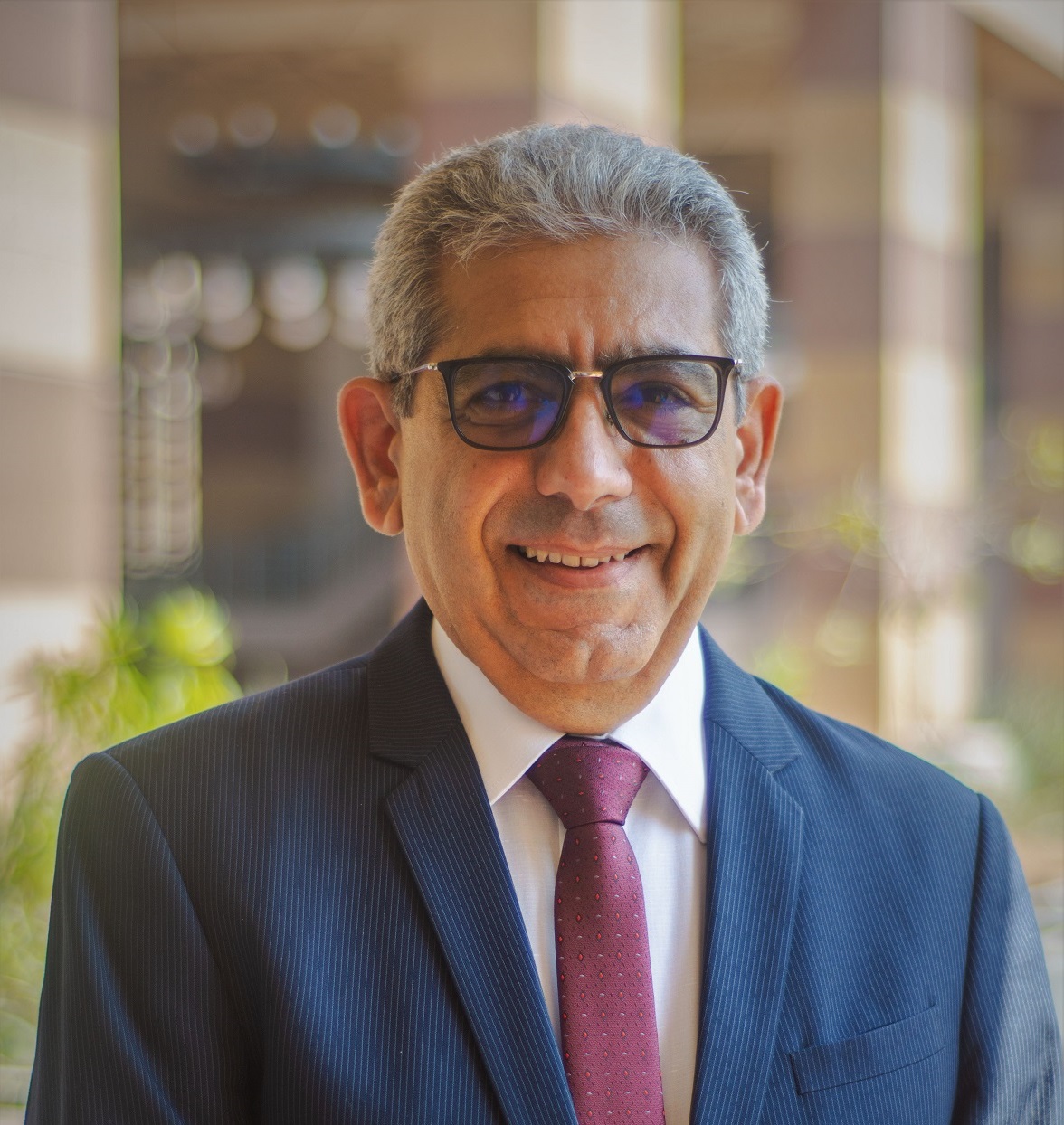 A man is smiling and wearing a suit and glasses