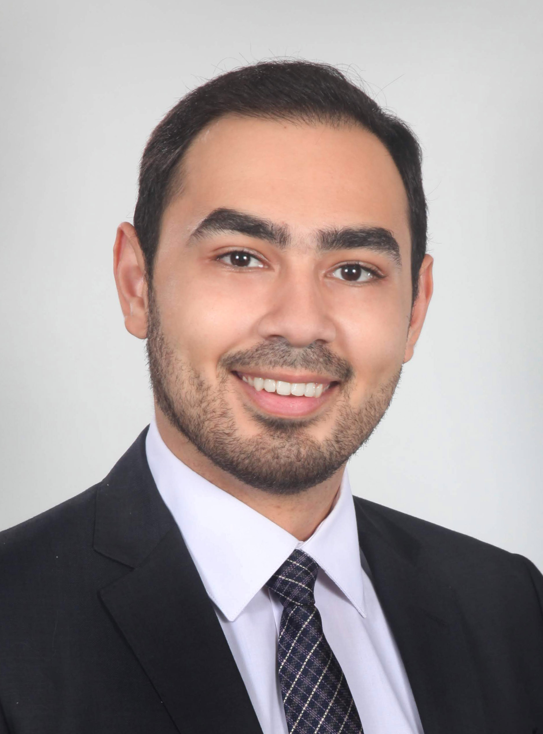 Head shot of a man smiling wearing a suit and tie