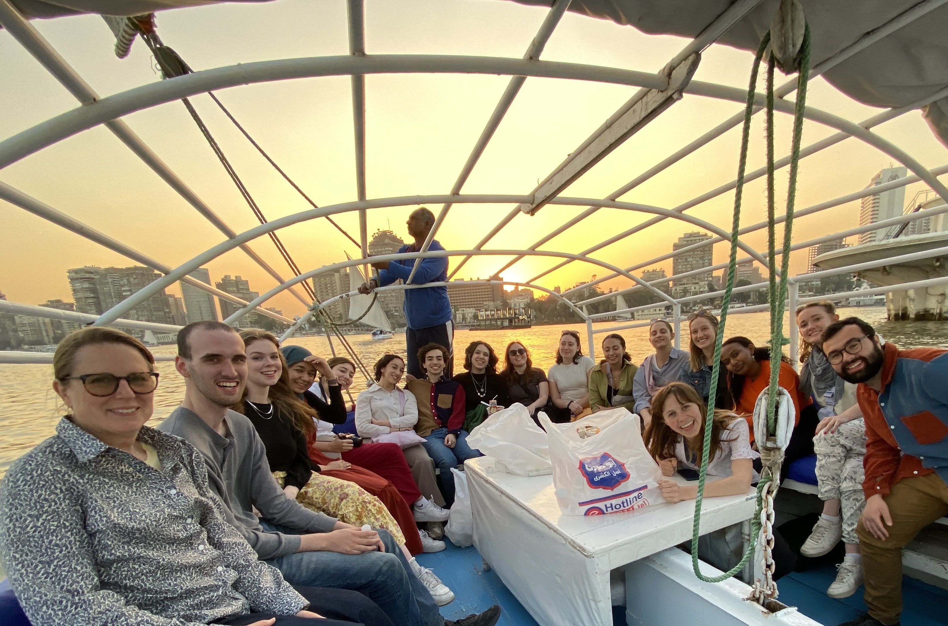 people on a felucca boat on the Nile, smiling as the sun sets behind them