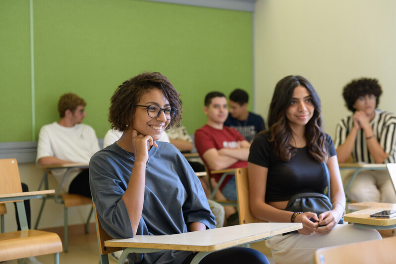 students sit in a classroom at AUC in front of a green wall