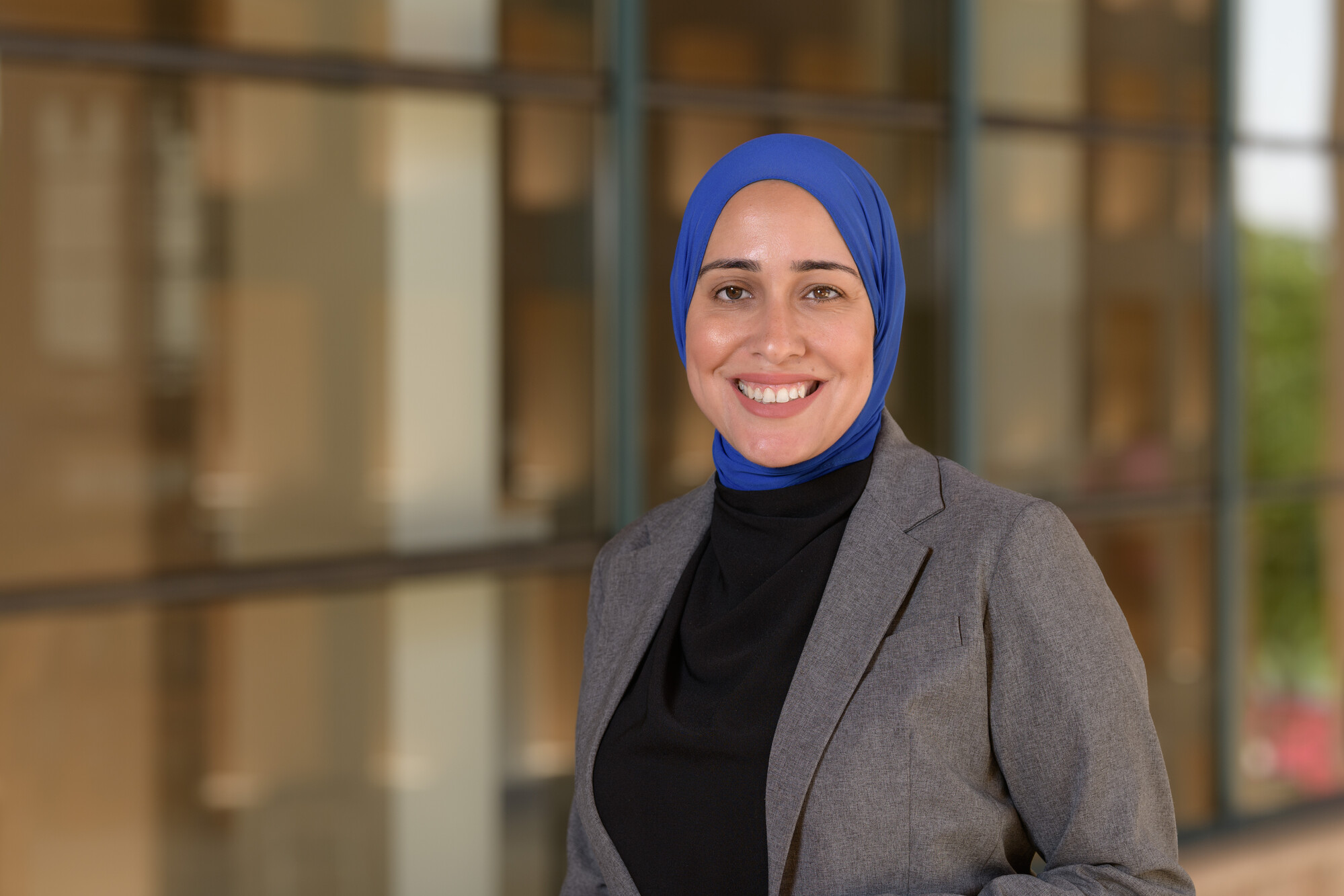 A veiled woman wearing a suit smiling in an outdoor setting