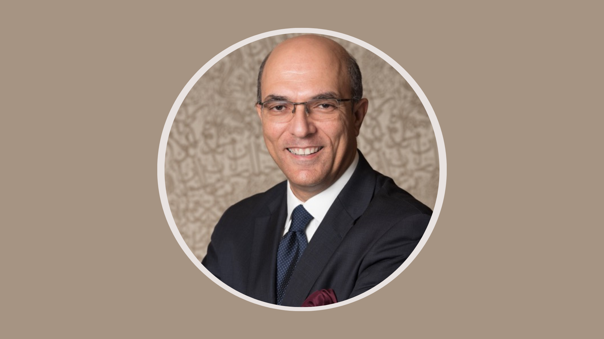 Man with glasses and formal attire smiles