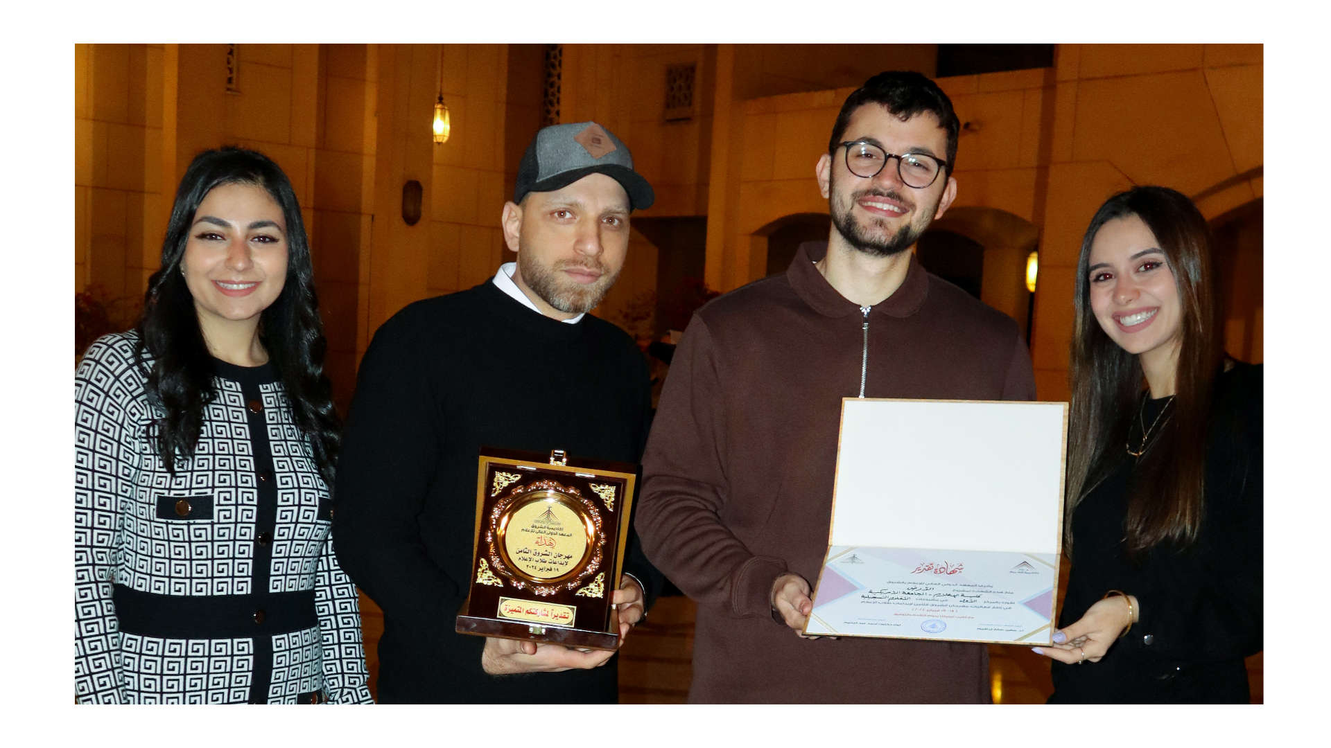 Two men and two women stand holding a plaque