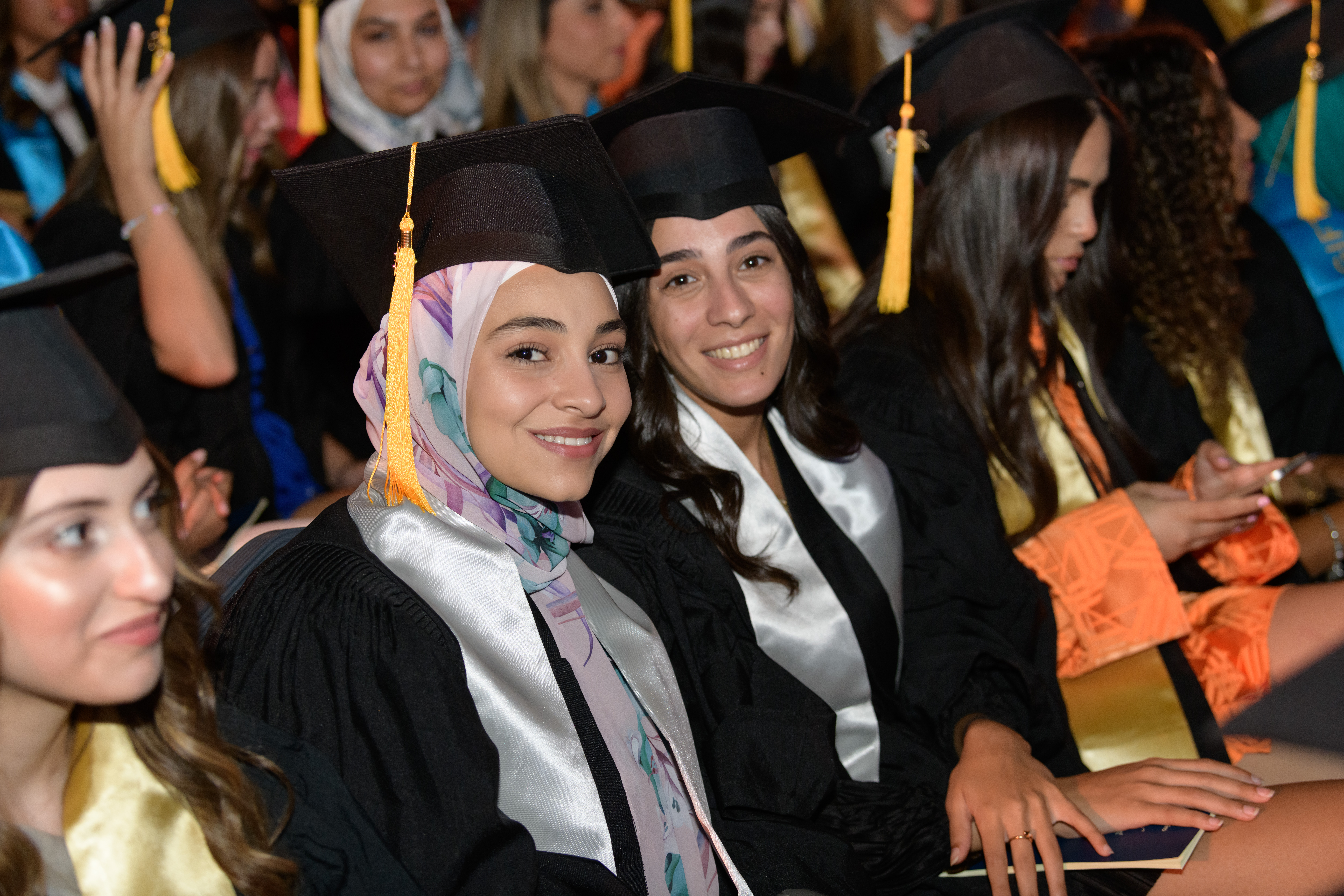 Students in caps and gowns smile in a crowded room