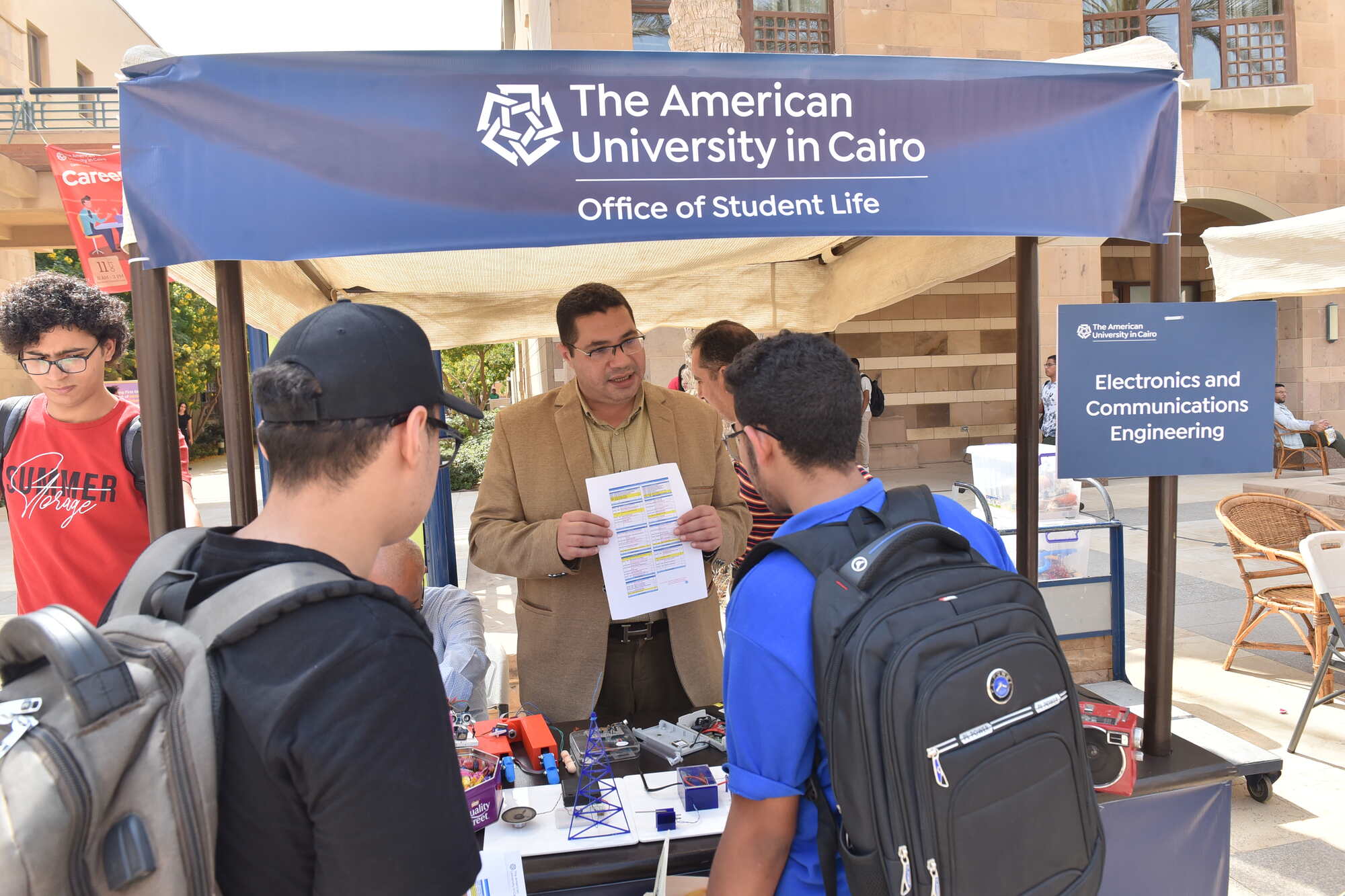 2 new students talking to professor about courses in Explore the Disciplines Fair at AUC