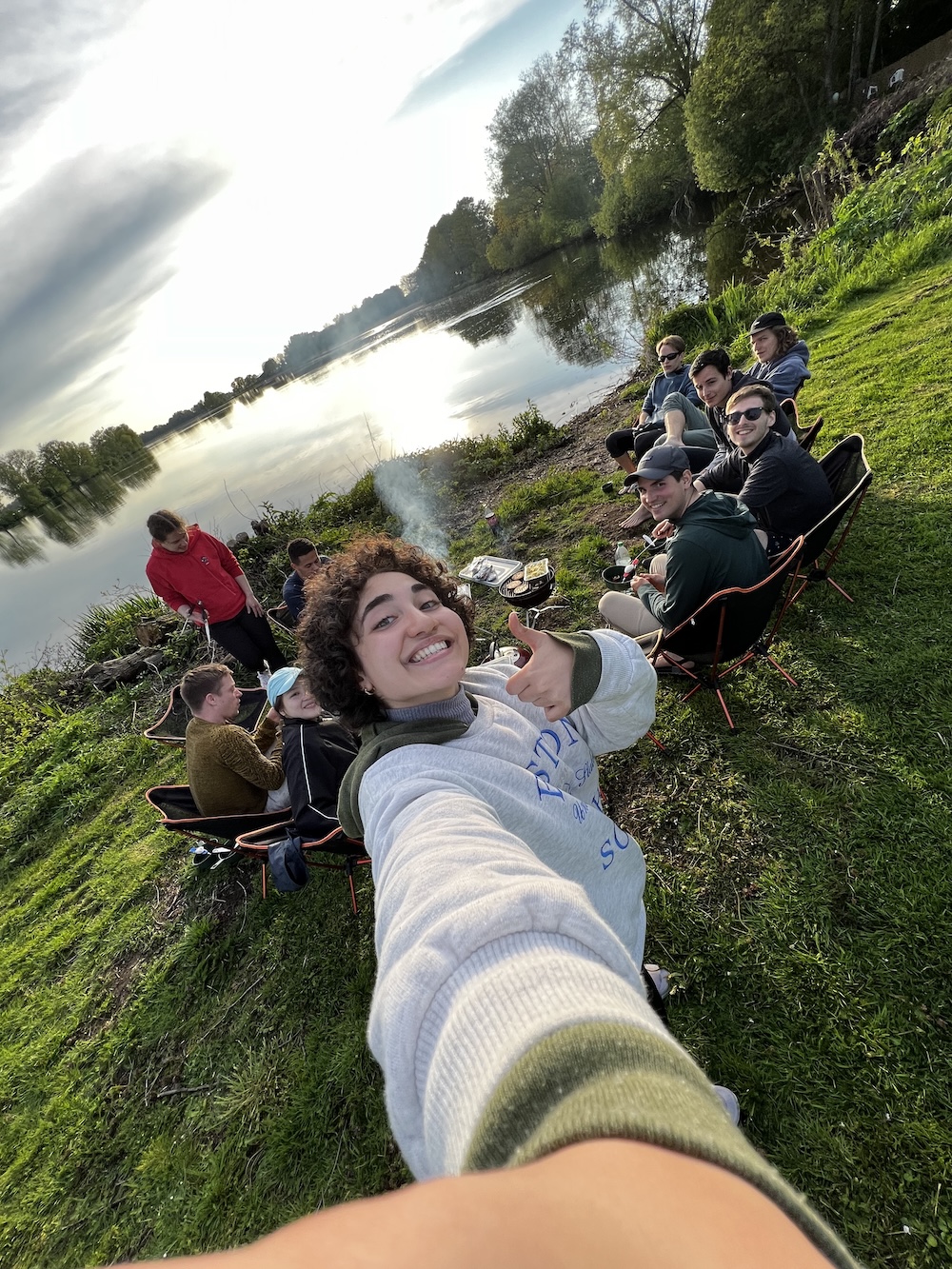 Female student taking a selfie with friends by a lake