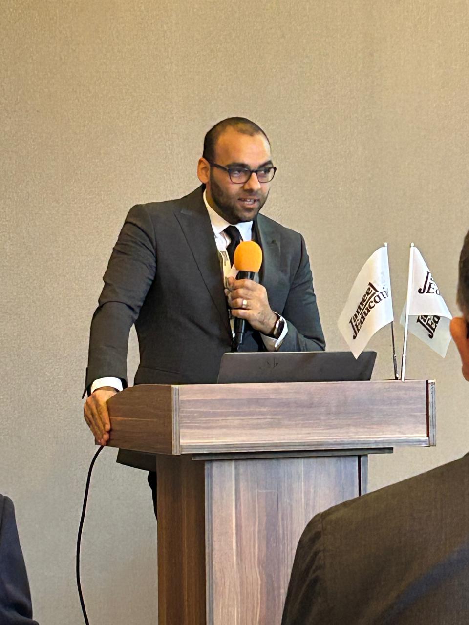A young man in a suit holding a mic and standing behind a podium