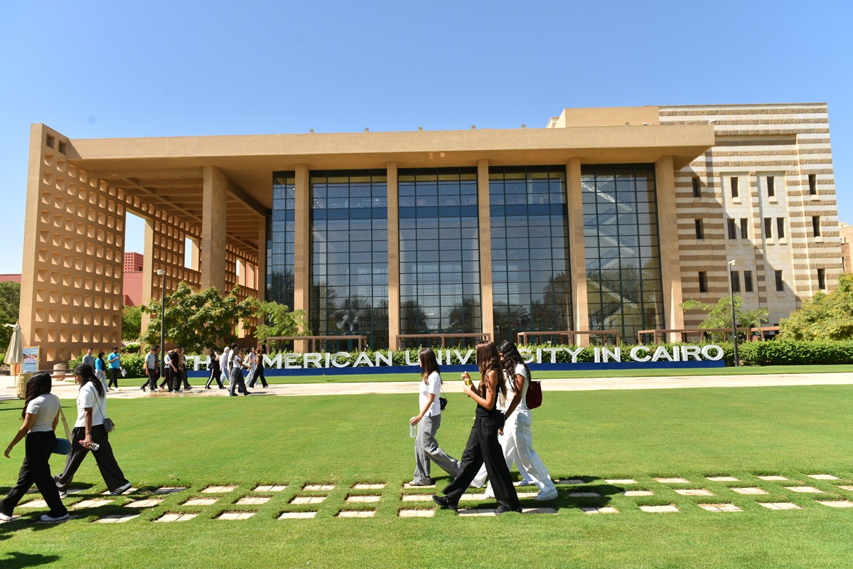 Students walking in front of a building. Text: The American University in Cairo