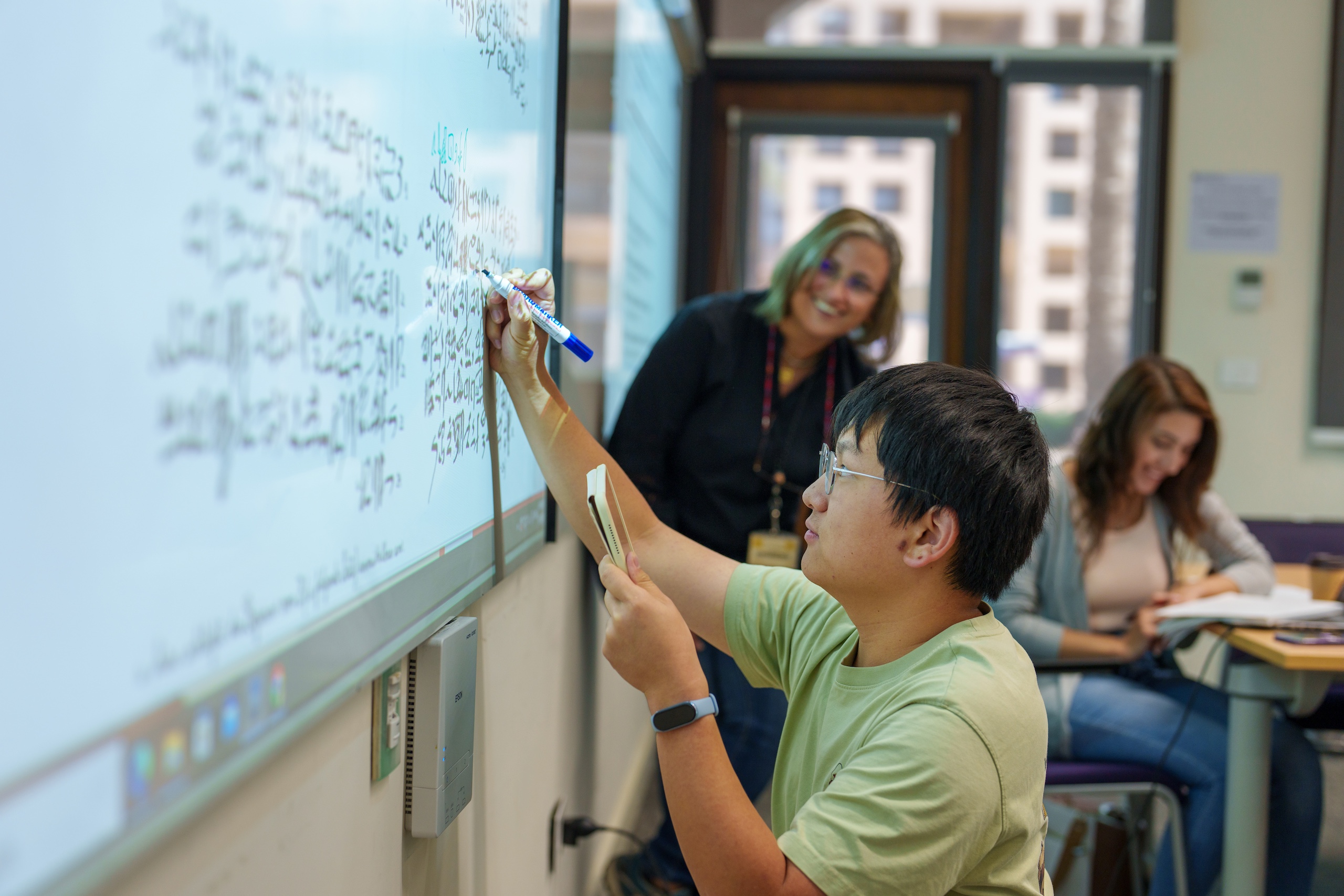 Student writing on a smart board in an active learning classroom