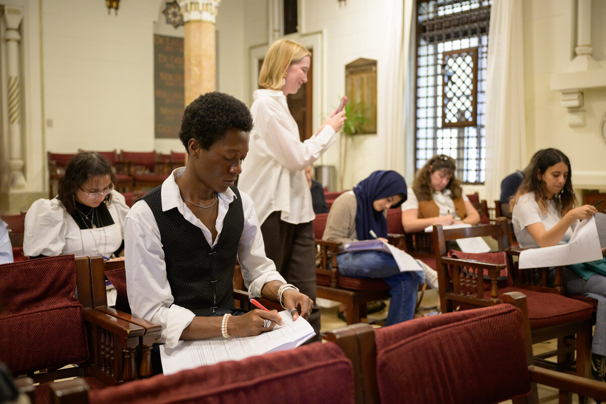 Professor Nina Ellis photographs her seated class while the class writes.