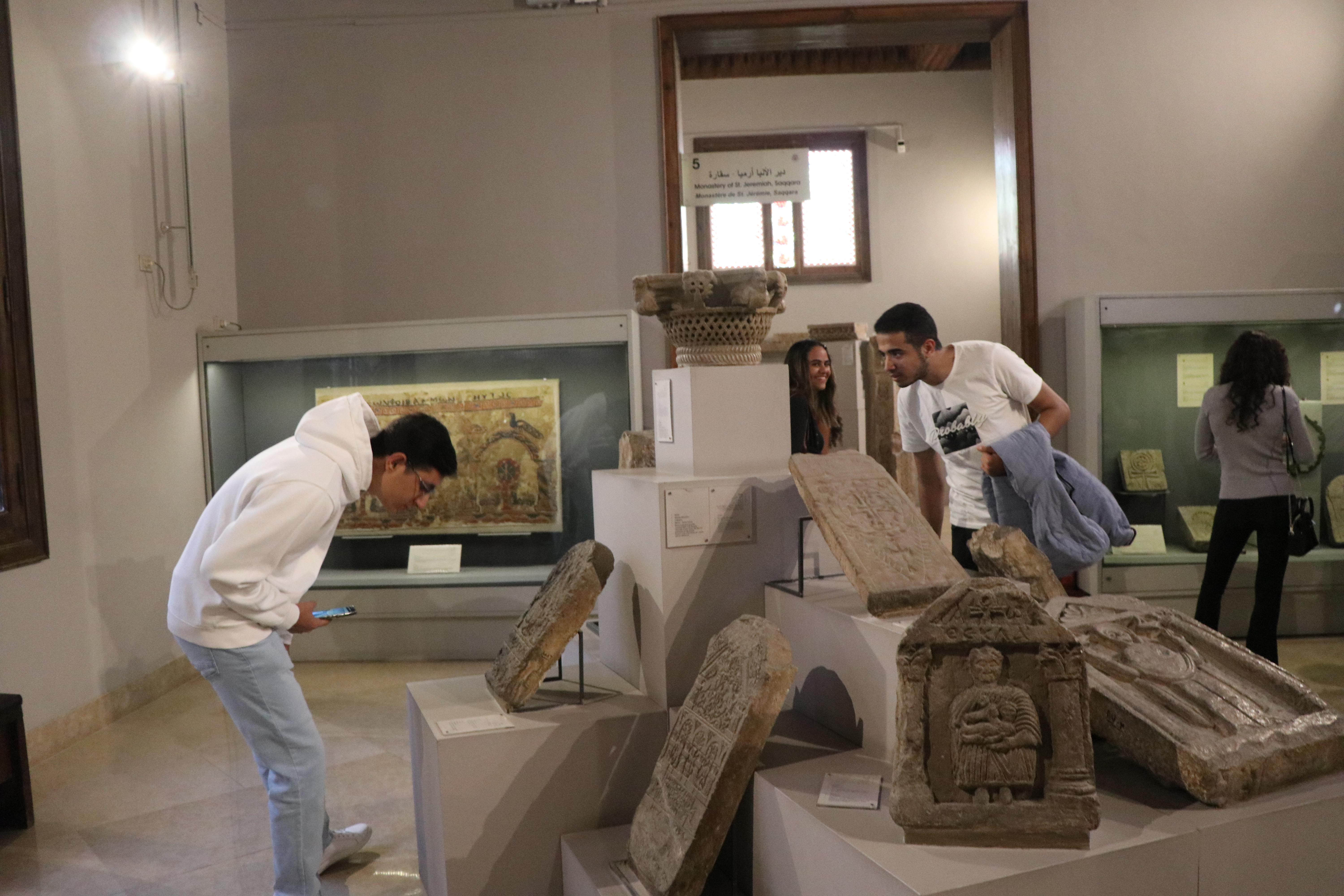 Students bending down and standing in front of Coptic monuments to examine them